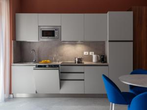 a kitchen with white cabinets and a table and blue chairs at Numa Rome Trastevere in Rome