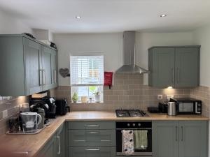 Una cocina con gabinetes verdes y una estufa. horno superior en ADI Holiday Home Lurgan, en Lurgan