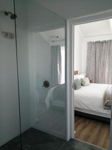 a bedroom with a bed and a glass door with a mirror at Skye in Paternoster