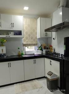 a kitchen with white cabinets and a black counter top at CUTE Homestay in Tumpat