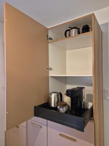 a small kitchen with white cabinets and pots and pans at Studio proche de Metz in Sanry-lès-Vigy +3 photos