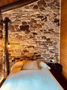 a stone wall with a bed in a room at Casa Arxemil in Sarria