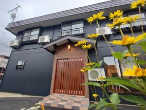 草津町にある草津温泉お宿きみのやの木製のドアと黄色い花が飾られた青い家
