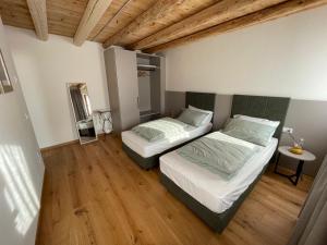 Dos camas en una habitación con suelo de madera. en Agriturismo I Giardini di Ron, en Valdobbiadene