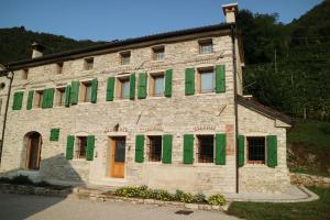 un antiguo edificio de piedra con ventanas con contraventanas verdes en Agriturismo I Giardini di Ron, en Valdobbiadene