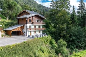 a house on the side of a hill with trees at Le Bord Du Nant in Arâches-la-Frasse