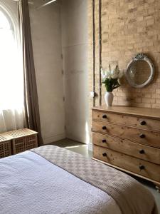 a bedroom with a bed and a dresser with a mirror at Basils Bolthole in Darsham