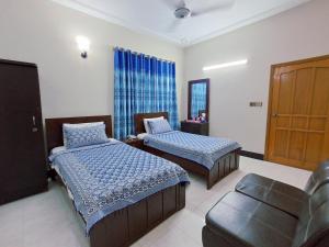 una camera d'albergo con due letti e un divano di Rose Palace Guest House a Karachi Altre 62 foto