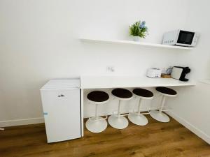 a kitchen with three stools and a counter with a refrigerator at Hostal Ruano in Madrid