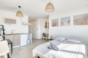 a white bedroom with a bed and a kitchen at L'instant Zen - CNPE Bugey - Centre Meximieux in Meximieux