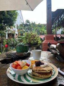a table with a plate of breakfast food and a bowl of fruit at Hostal Estrella de Agua in Salento
