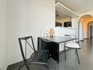 a black desk and two chairs in a kitchen at La Parenthèse Corse in LʼÎle-Rousse