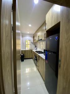 a kitchen with a black refrigerator and wooden cabinets at Abuja City Tourist's Home in Abuja