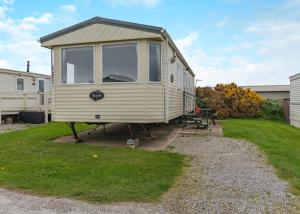 a tiny house is parked in a yard at Rowanbank Caravan Park in Beckfoot