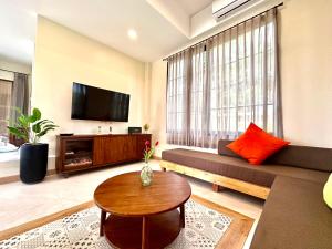 a living room with a couch and a tv at Mimi Pool Villa Chiangmai in Chiang Mai