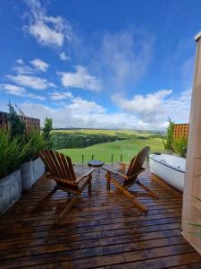 two chairs and a table on a wooden deck at Parador dos Canyons in Cambará
