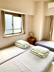 zwei Einzelbetten in einem Zimmer mit Fenster in der Unterkunft Nagoya Station is nearby, convenient for shopping in Nagoya