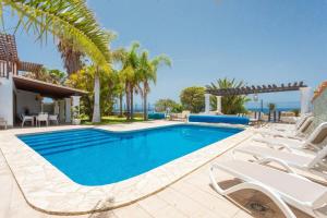 een zwembad met witte stoelen en de oceaan bij La Quinta Heights -6 Bed Villa-private Pool in San Miguel de Abona