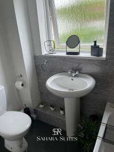 a bathroom with a sink and a toilet and a window at Modern 2BR Flat - Sleeps 4 - Newcastle City & St James - Parking in Elswick