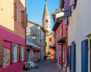 an alley in an old town with a clock tower at Functional studio by the beach-Beahost in Porto Santa Margherita di Caorle +12 photos