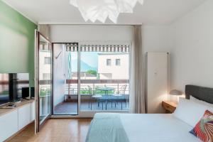 a bedroom with a bed and a view of a balcony at Vinorum Studio by Quokka 360 - Cozy and sunny with balcony in Massagno