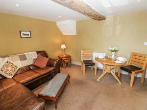 een woonkamer met een bank en een tafel bij Ewe Cottage in Masham