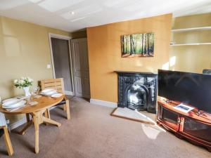 een woonkamer met een tafel en een open haard bij Ewe Cottage in Masham