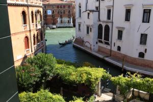 a canal with a boat in the water between buildings at Pensione Accademia - Villa Maravege in Venice
