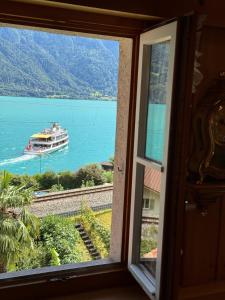 una finestra con vista su una barca in acqua di Lakeview Swiss Chalet with Hot Tub near Interlaken a Niederried