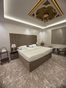 a bedroom with a large bed and a table and chairs at شقق رومكس Rumex apartments in Al-Salam