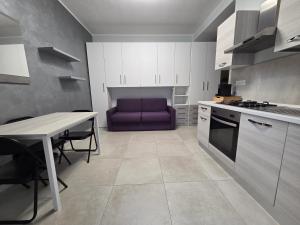 cocina con mesa y sofá púrpura en Ceriale Suite, en Ceriale