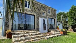 a stone house with large windows and a lawn at The Cliffs - Picon Seaside Cottage in Loiba