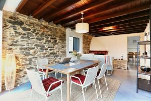 a dining room with a table and chairs and a stone wall at The Cliffs - Picon Seaside Cottage in Loiba +34 photos