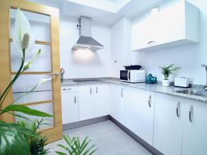 a kitchen with white cabinets and a sink at The Cliffs - Sunset Village Beach 1A in Viveiro