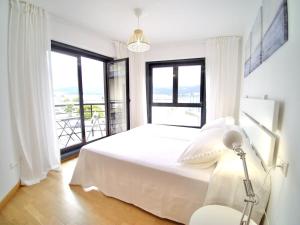 a bedroom with a white bed and a large window at The Cliffs - Sunset Village Beach 1A in Viveiro +28 photos