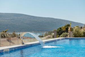 a water fountain in a swimming pool with a hill in the background at Bella Vista Lux apartment in Baošići