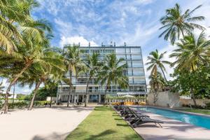un gran edificio con palmeras y una piscina en Beachfront 4beds Jacuzzi Privacy Full Kitchen, en La Puntica de Juan Dolio
