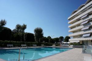 a swimming pool in front of a large apartment building at Seaview studio for two-Beahost in Porto Santa Margherita di Caorle