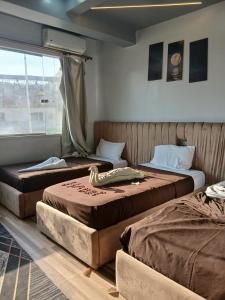 two beds sitting in a room with a window at Pyramids Acme Inn in Nazlet el-Sîsi