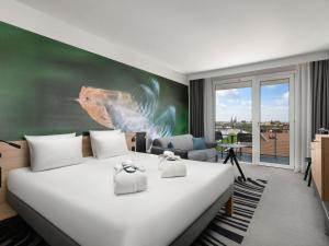 a hotel room with a bed with towels on it at Novotel Szeged in Szeged