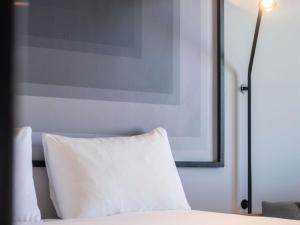 a bed with a white pillow and a picture on the wall at ibis Strasbourg Centre Gare in Strasbourg