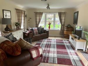 a living room with a couch and a tv at Struan Cottage in Ballater