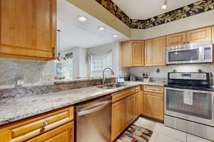 una cucina con armadietti in legno ed elettrodomestici in acciaio inossidabile di Coastal condo with pool, lanai, washer/dryer, & elevator a Saint Augustine Beach
