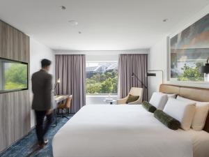 a man standing in a hotel room with a bed at Novotel Sydney Darling Square in Sydney