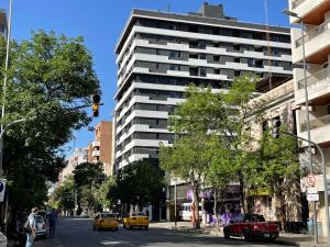 a tall white building on a city street with cars at Rent a Flat Nueva Cordoba in Cordoba