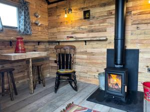 a fireplace in a log cabin with a table and chair at Shepherd's Huts at Cotswold Hills Country Park in Chipping Norton