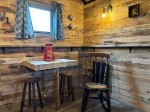 a bar in a log cabin with two stools at Shepherd's Huts at Cotswold Hills Country Park in Chipping Norton