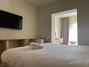 a bedroom with a bed with a flat screen tv on the wall at Adonis Sanary Grand Hôtel des Bains in Sanary-sur-Mer