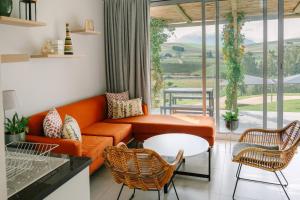 a living room with an orange couch and chairs at The Salene Hotel & Apartments in Stellenbosch