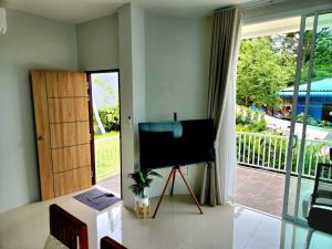 Una sala de estar con televisión y balcón. en Wildflower phangan, en Haad Pleayleam